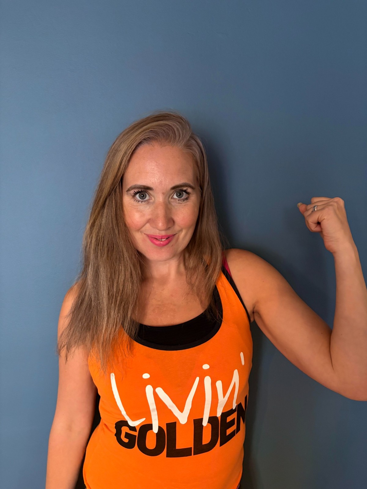Debs, your Zumba Gold instructor, smiling in her orange Livin’ Golden top